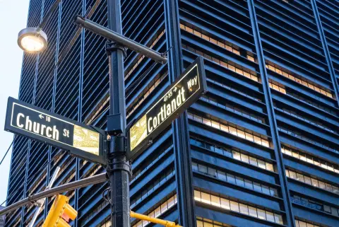 Panneaux Church Street et Cortlandt Way devant une façade vitrée au crépuscule, New York