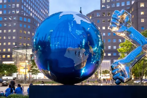Sculpture d'un globe métallique et d'un poing levé devant les tours au crépuscule, New York