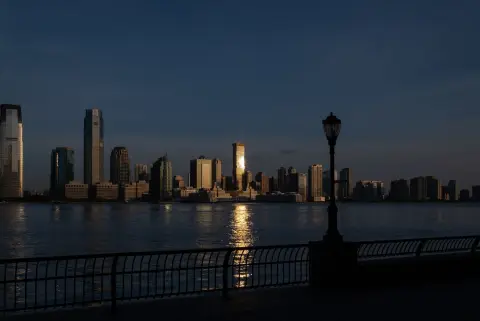 Skyline au crépuscule reflétée sur l'eau derrière un lampadaire, New York
