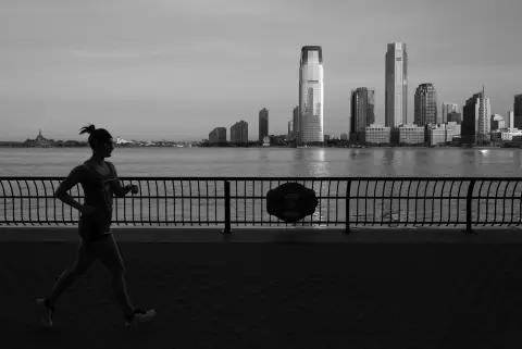 Coureuse silhouettée longeant la promenade face aux gratte-ciel, New York