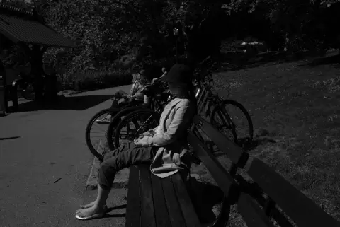 Femme assise sur un banc à l'ombre pres de vélos garés, New York
