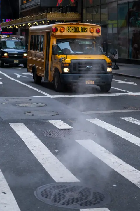 Bus scolaire jaune traversant un carrefour embrumé de vapeur, New York