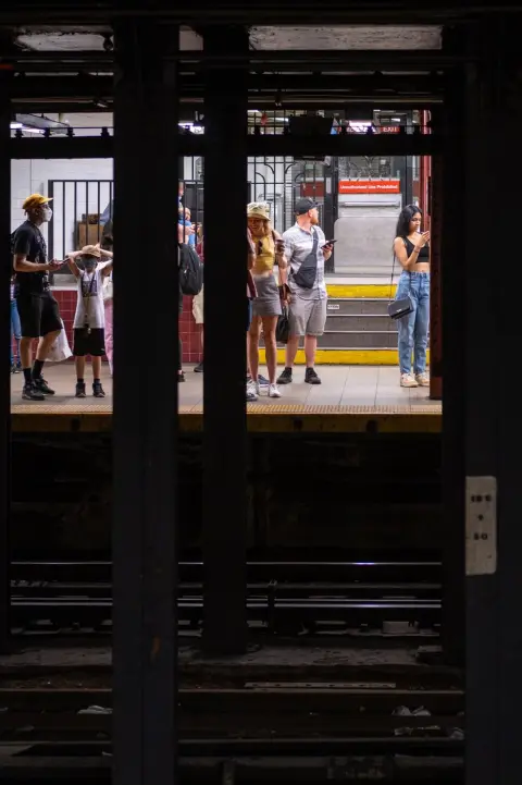 Voyageurs attendant sur le quai vus entre les poutres du métro, New York