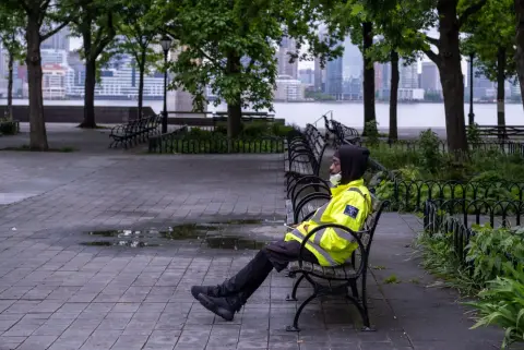Agent en gilet jaune fluo assis sur un banc face à la rivière, New York