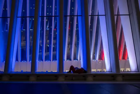Personne allongée au pied des nervures illuminées de l'Oculus la nuit, New York