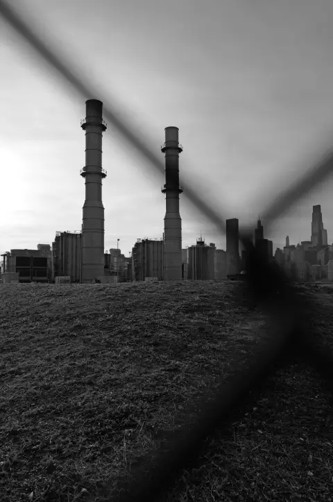 Cheminées industrielles vues à travers un grillage, skyline en fond, New York