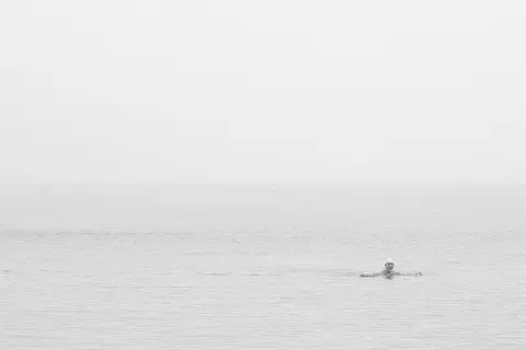 Tête d'un nageur émergeant d'une mer laiteuse et brumeuse, New York