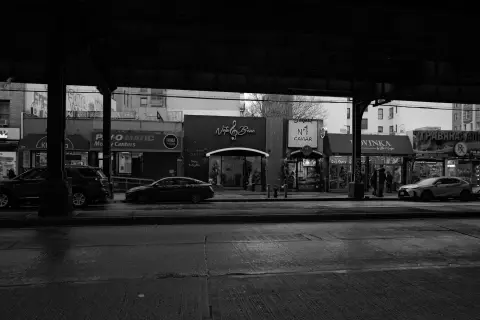 Rue commerçante sous les voies aériennes du métro la nuit, New York