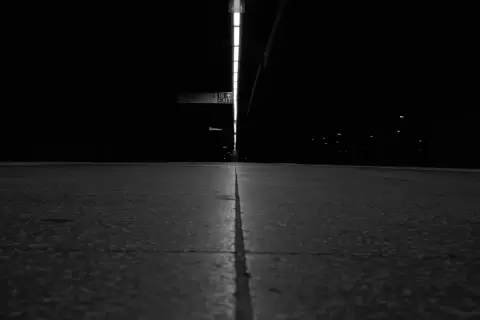 Couloir de métro sombre menant vers un panneau Exit lumineux, New York