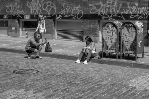 Trois amis photographiant des boîtes aux lettres tagués dans une rue pavée, New York
