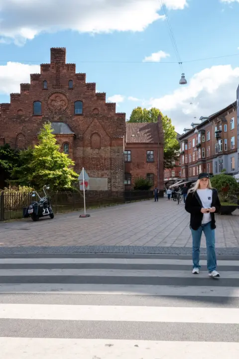 Une femme traverse devant un pignon de briques à redents, Odense