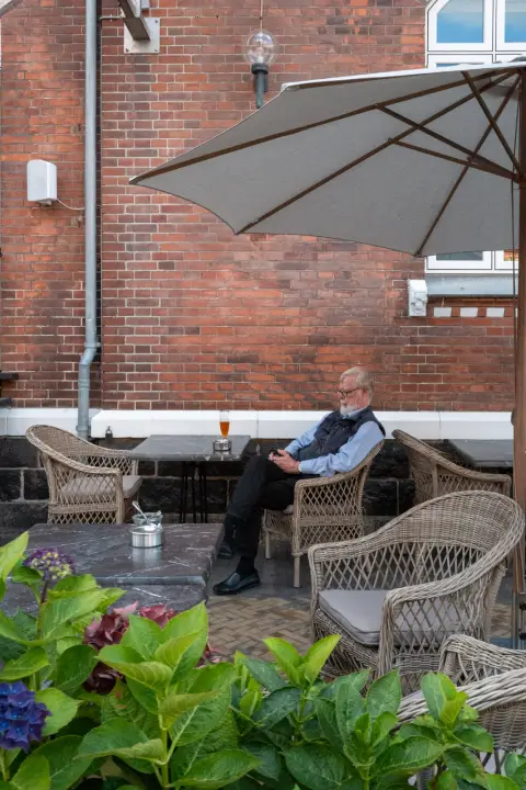 Un homme âgé seul sur une terrasse, derrière les hortensias, Odense