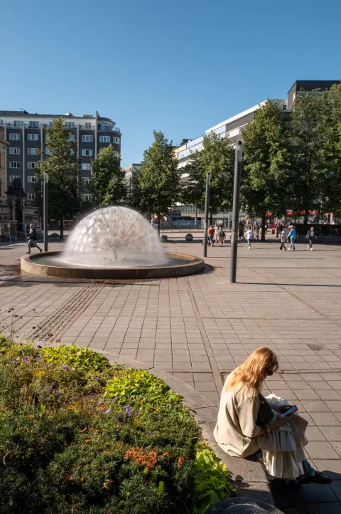 Une jeune femme lit au bord d’un massif, près d’une fontaine en dôme, Oslo