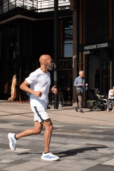 Un coureur en blanc passe devant les vitrines, Oslo