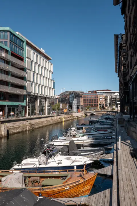 Un canal bordé de bateaux entre des immeubles modernes, Oslo