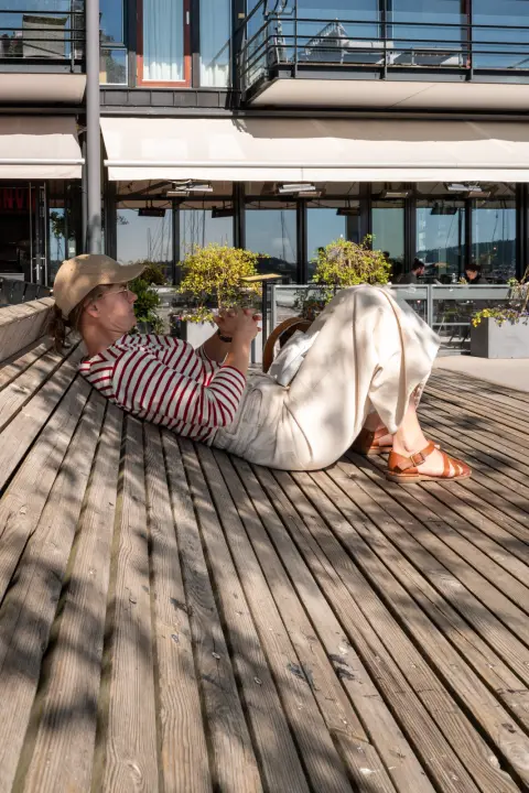 Une femme au chapeau de paille allongée sur un banc de bois, Oslo