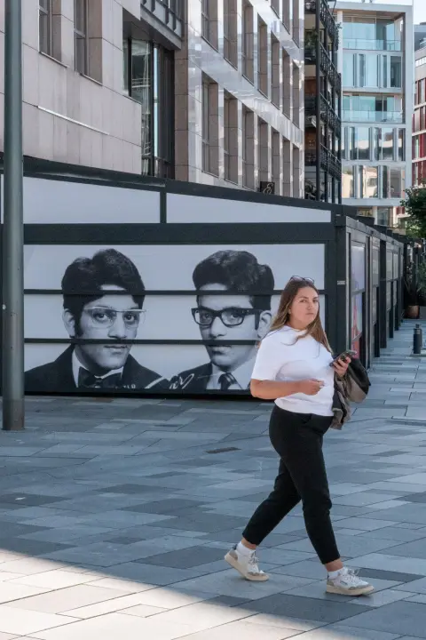 Une passante en blanc devant deux portraits géants, Oslo