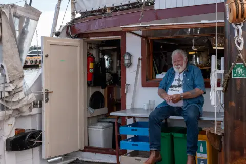 Un vieux marin à barbe blanche assis à la porte de la cuisine du bateau, Oslo