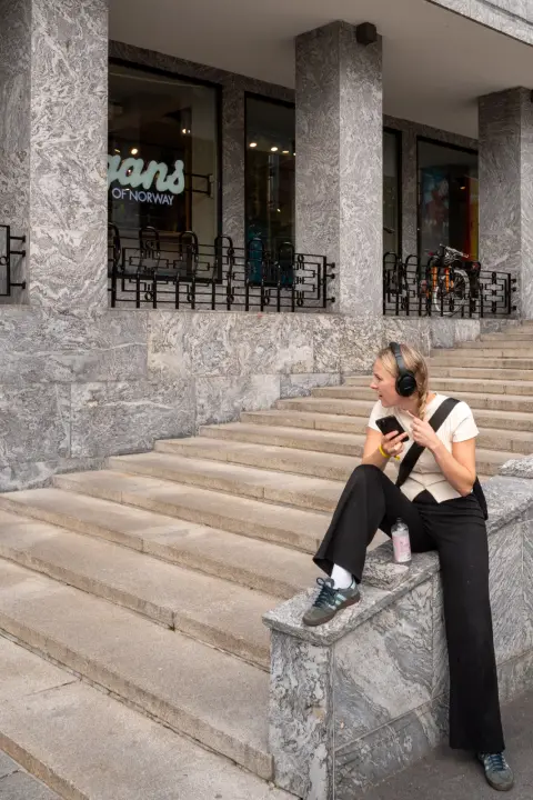 Une femme au casque audio assise sur des marches de pierre, Oslo