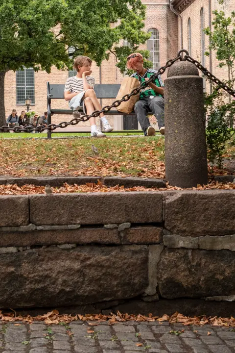 Deux hommes sur un banc derrière une chaîne, près d’une église, Oslo