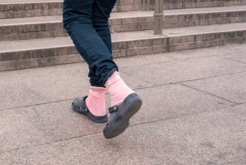 Des chaussettes roses dans des sabots noirs montent les marches, Oslo