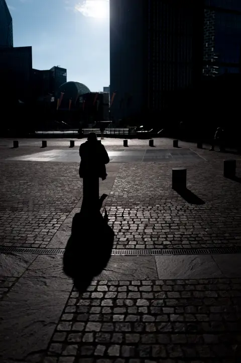 A silhouette and its shadow on the cobbles, between the towers, Paris