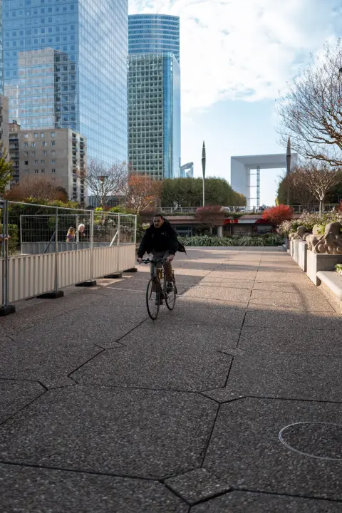 A cyclist on the esplanade, the Grande Arche in the distance, Paris