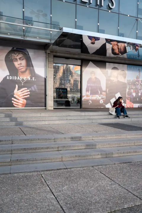 Someone sitting on the steps in front of a giant advertising window, Paris