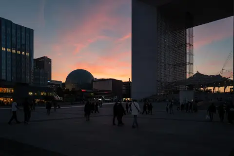 The crowd on the esplanade at dusk, the dome and the Arche against the light, Paris
