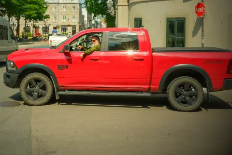 Un pick-up rouge tourne au carrefour sous un panneau « Arrêt », Québec