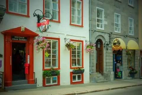 Façade blanche aux fenêtres rouges d’une boutique du Vieux-Québec, fleurs aux fenêtres, Québec