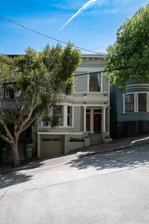 Maison victorienne verte à porte rouge sur une rue escarpée, San Francisco