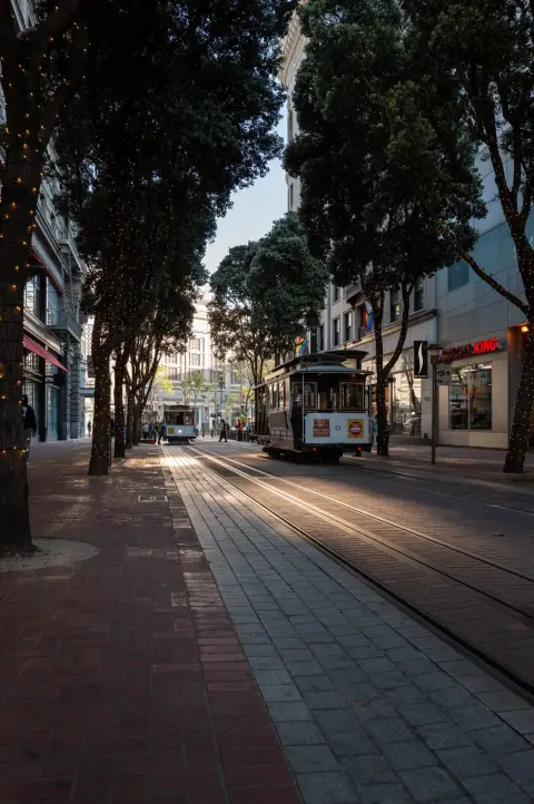 Deux cable cars se croisant sous une allée d'arbres illuminés, enseigne Burger King, San Francisco