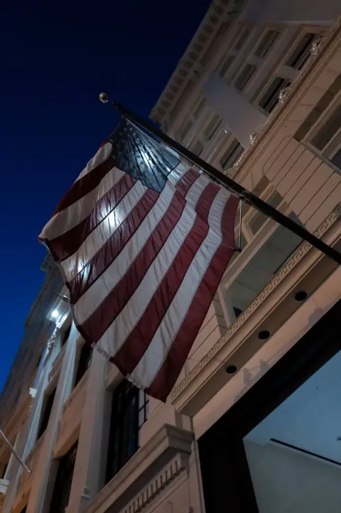 Drapeau américain illuminé flottant devant une façade classique de nuit, San Francisco
