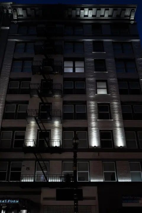 Façade d'immeuble aux échelles de secours éclairées par des spots la nuit, San Francisco
