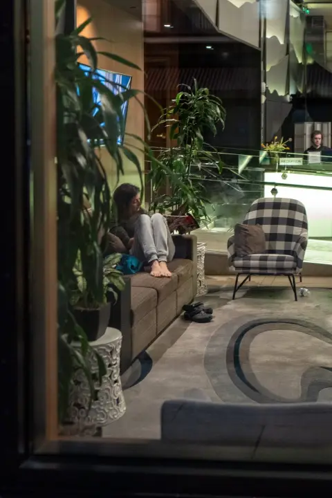 Femme pieds nus lisant sur un canapé dans le hall d'un hôtel, vue à travers la vitrine, San Francisco