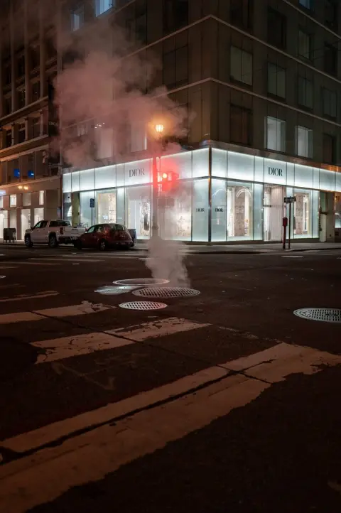 Vapeur nocturne s'élevant devant l'angle vitré de la boutique Dior, feu rouge allumé, San Francisco