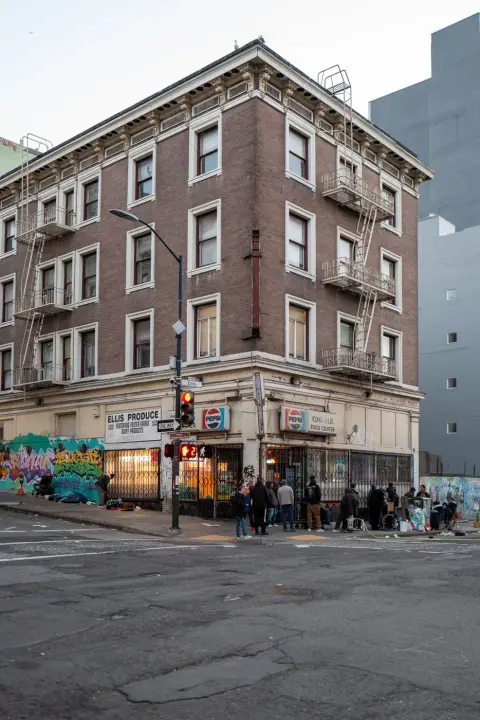 Immeuble de briques à l'angle avec les enseignes Ellis Produce et Pepsi, petit groupe sur le trottoir, San Francisco