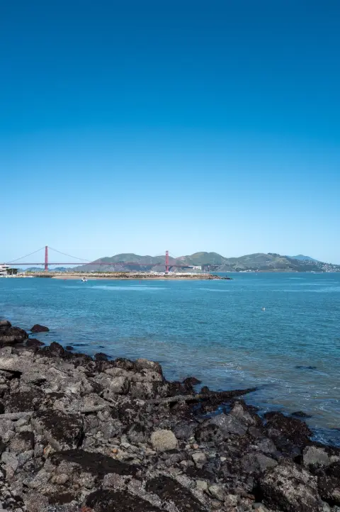 Golden Gate Bridge vu depuis un rivage rocheux, baie d'un bleu profond, San Francisco