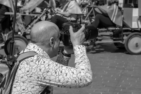 Photographe chauve en chemise à motifs, de dos, qui vise un char, Zinneke Parade, Bruxelles (planche 028)