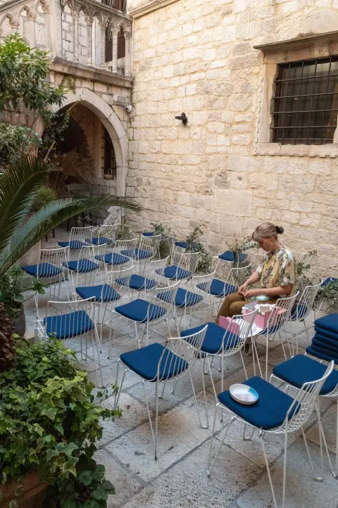 Rangees de chaises bleues installees dans une cour en pierre pour un evenement, Split