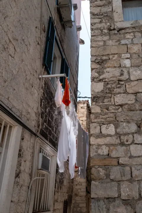 Linge blanc suspendu entre deux facades en pierre, Split