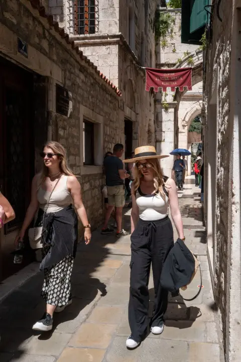 Deux passantes en tenue d'ete sous une banniere Zlatna Vrata, Split