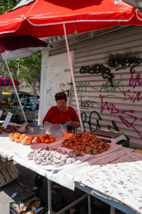 Marchande de rue preparant des beignets et abricots sous un parasol rouge, Split