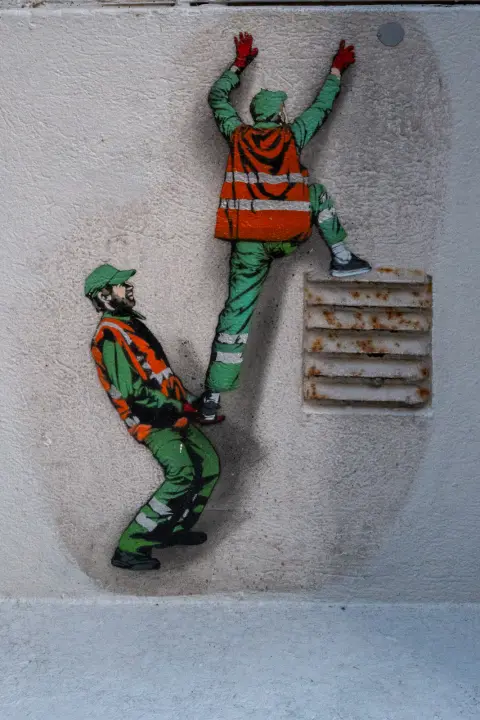 Deux ouvriers en gilet orange escaladent un mur, peints au pochoir, Stavanger