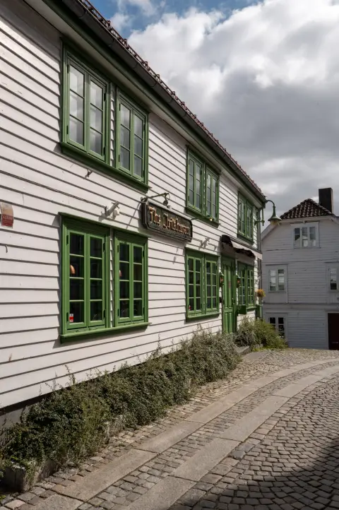 Une maison de bois blanche aux fenêtres vertes au coin d’une ruelle, Stavanger