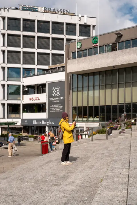 Une femme en veste jaune photographie la place, Stavanger