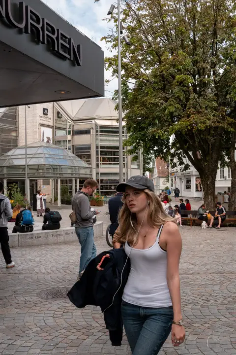 Une jeune femme en débardeur blanc traverse la place, Stavanger