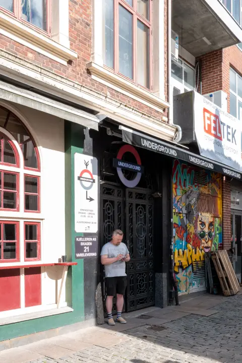 Un homme adossé à l’entrée d’un bar à l’enseigne « Underground », Stavanger