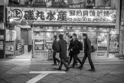 Hommes en costume passant devant la devanture d’un restaurant de fruits de mer, Tokyo